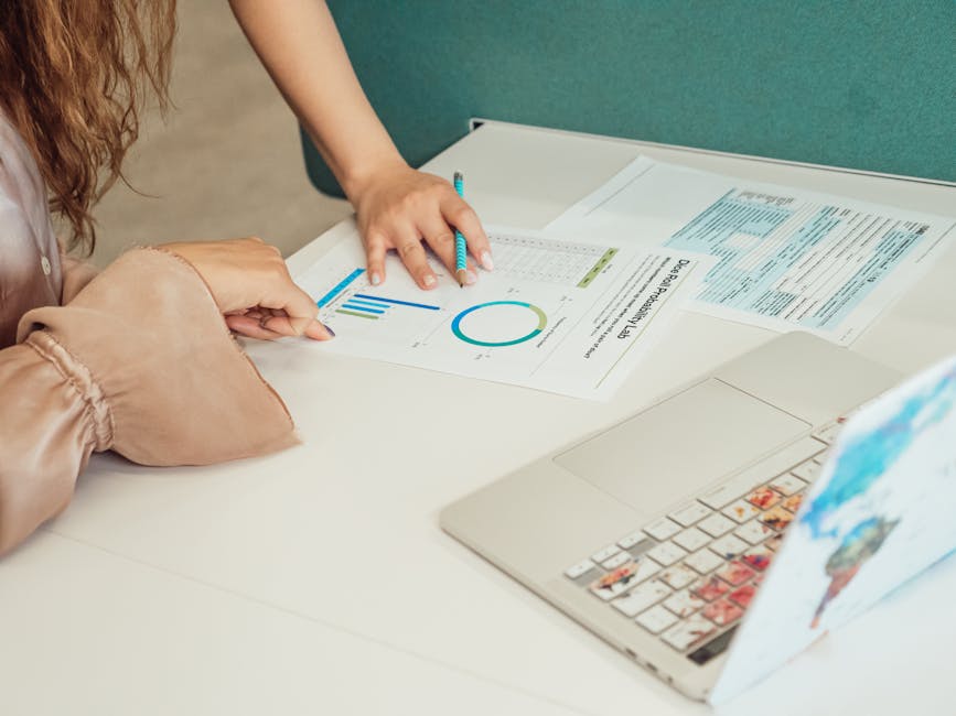 Two people analyzing business graphs and documents at an office desk.